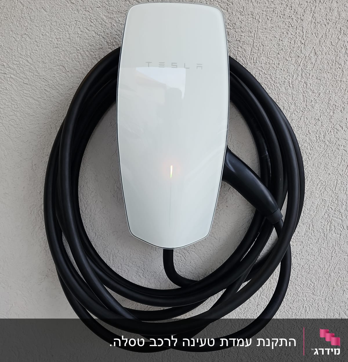 מטען טסלה עם כבל שחור תלוי על קיר